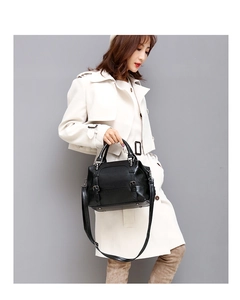 Detail of a black oil-wax leather Boston bag held by a model in a white trench coat