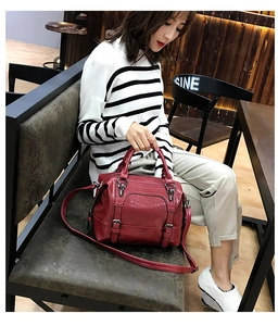 Detail view of dark red wax leather Boston bag with decorative metal pin buckles