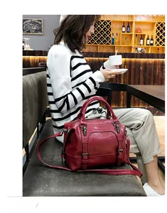 Detail view of red oil wax leather boston bag with metal buckles and adjustable strap