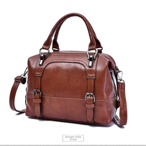 Detailed side view of a brown vintage oil wax leather boston bag with bronze metal buckles