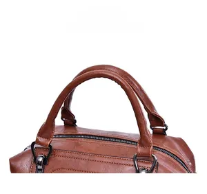 Detailed close-up of brown oil wax leather bag featuring dual handles and metallic hardware