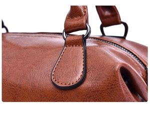 Detail of brown oil wax leather handbag showing lychee grain and black metal ring buckles