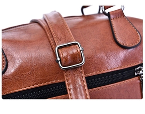 Close-up of retro brown oil wax leather bag featuring metal buckle and zipper detail