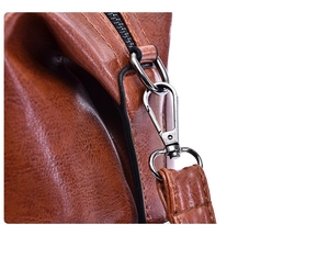 Detailed macro view of dark brown leather handbag with silver metal hook and zipper
