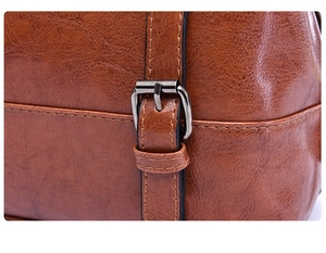 Macro detail of brown oil wax leather bag featuring a metal buckle and neat stitching