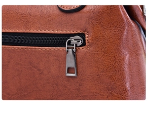 Detailed macro view of brown lychee grain leather handbag with dark gray metal zipper