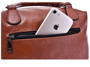 Detail view of brown oil wax leather pillow bag featuring a functional rear zipper pocket