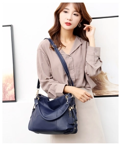 Dettaglio borsa a tracolla blu navy in pelle martellata con hardware dorato e nappa