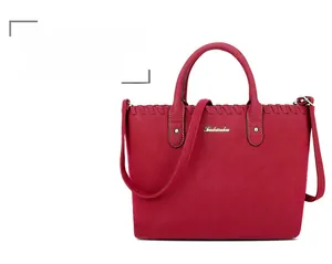 Détail du sac à main rouge mat avec bords en cuir tressé et plaque logo dorée élégante