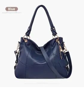 Dettaglio borsa a mano in pelle blu con finiture dorate e ciondolo a cuore