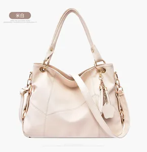 Dettaglio della borsa beige con grana litchi, nappa decorativa e tracolla regolabile