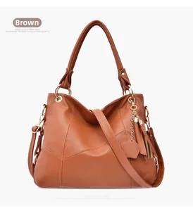 Dettaglio della borsa tote marrone con nappa in pelle e ciondolo a cuore su sfondo bianco