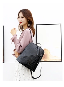 Detailed view of black crocodile pattern leather backpack with stylish diagonal zipper