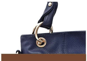 Dettaglio degli anelli in metallo dorato e trama in pelle blu scuro della borsa
