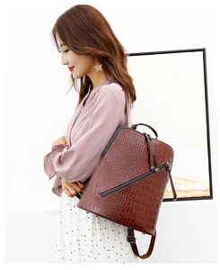 Close-up of a dark brown crocodile texture backpack with decorative diagonal zippers