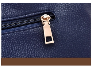 Dettaglio della cerniera dorata sulla borsa in pelle blu navy con trama a grana