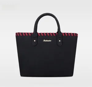 Vue de face du sac cabas en cuir mat noir avec bord tressé rouge et logo doré chic