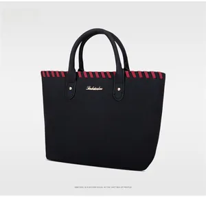 Détail du sac cabas noir mat avec coutures rouges et rivets métalliques dorés