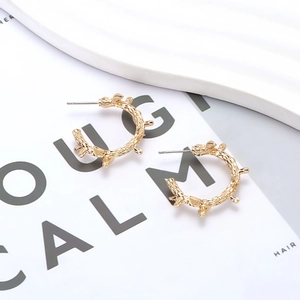 Retro golden C-shaped hoop earrings with unique thorn texture on minimalist magazine base