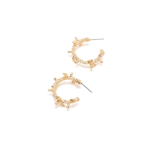 Close-up of vintage golden C-shape earrings featuring unique thorn branch texture detail