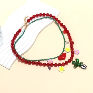 Collier double couche de perles colorées avec pendentifs cactus et cœur sur support blanc
