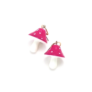 Detail of pink resin mushroom earrings featuring white spots and gold hooks
