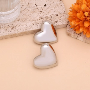 Macro shot of silver heart earrings on travertine stone with warm lighting