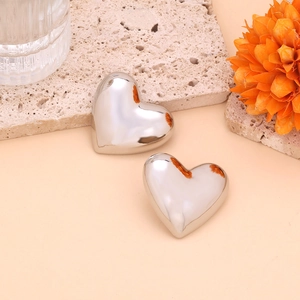 Detailed macro view of mirror-polished silver heart earrings on a natural stone base