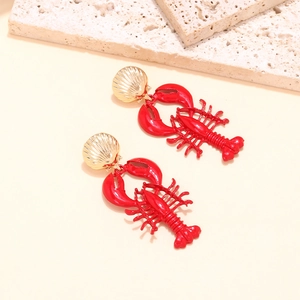Detail view of red lobster dangle earrings with golden shells on a textured stone surface