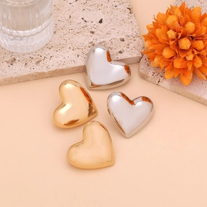 Detailed view of polished heart-shaped metallic earrings in gold and silver finishes