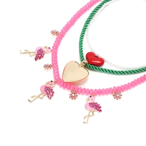 Détail macro du collier multi-rangs avec pendentifs flamants roses et coeurs en cristal
