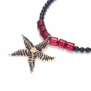 Macro detail of enamel starfish pendant with black and red beaded choker necklace