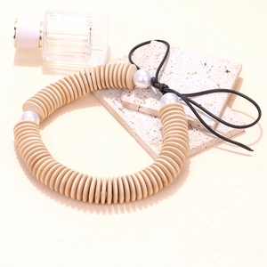 Détail d'un collier artisanal en perles de bois avec perles blanches sur pierre beige