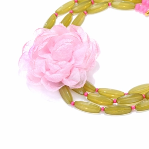 Close-up of olive green layered beads and large pink fabric flower on a necklace
