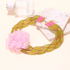 Detail of bohemian triple-layer beaded necklace with large pink fabric flower