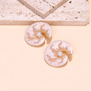 Détail macro de boucles d'oreilles conque rose avec texture marbrée, perle et or