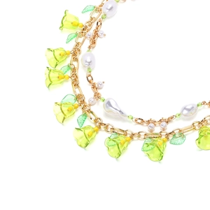 Dettaglio della collana a doppio strato con fiori verdi in resina e perle finte bianche