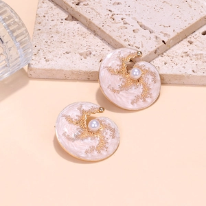 Détail de boucles d'oreilles spirales en émail rose avec perle et perles dorées