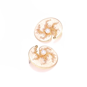 Gros plan de boucles d'oreilles coquillage en émail doré avec perle style rétro
