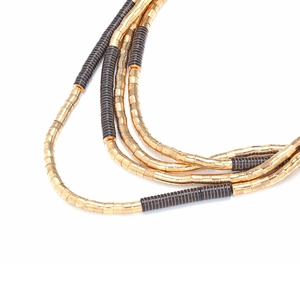 Macro detail of multi-strand beaded necklace with gold and black metallic cylinders