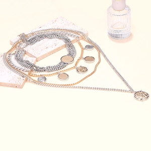 Détail de colliers géométriques superposés avec pendentifs pièces sur supports en pierre