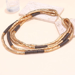 Detail of layered gold beaded cords and black textured accents on a waterfall necklace