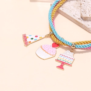 Macro detail of multi-strand braided birthday necklace with cupcake and hat enamel charms