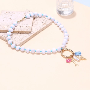Détail du collier océan avec perle, fleur et pendentifs en forme de coquillage doré