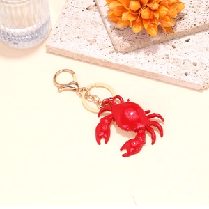 Cute red crab keychain with gold lobster clasp on a warm aesthetic decorative background