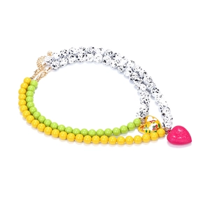 Detail of colorful beaded necklace with pink heart pendant and floral enamel charm