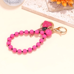 Pink beaded keychain with enamel tropical fish and heart charms on warm background