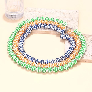 Detail of layered geometric beaded necklaces with colorful patterns on a stone display