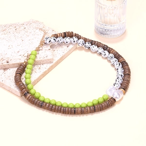 Détail d'un collier bohème en perles de bois avec pierre verte et perle baroque