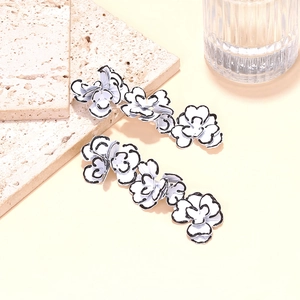 Detailed view of matte white floral earrings with black hand-painted edges on stone base